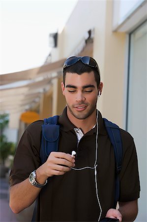 Jeune homme à l'écoute d'un lecteur MP3 et souriant Photographie de stock - Premium Libres de Droits, Code: 625-02932831