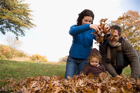 Couple and their daughter playing with leaves Stock Photo - Premium Royalty-Free, Code: 625-02932911