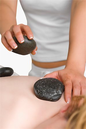 simsearch:685-02940844,k - Close-up of a massage therapist placing pebbles on a woman's back Fotografie stock - Premium Royalty-Free, Codice: 625-02933021