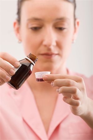 Female nurse pouring syrup into a bottle cap Stock Photo - Premium Royalty-Free, Code: 625-02933112