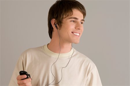 Gros plan d'un jeune homme à l'écoute d'un lecteur MP3 et souriant Photographie de stock - Premium Libres de Droits, Code: 625-02933133