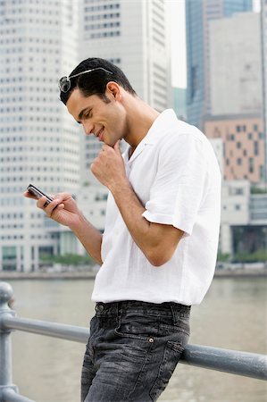 Side profile of a mid adult man text messaging and smiling Foto de stock - Sin royalties Premium, Código: 625-02933176