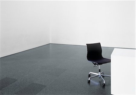 Office chair and desk in an empty room Fotografie stock - Premium Royalty-Free, Codice: 628-05817457