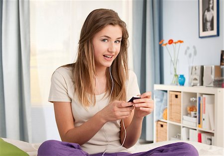 Teenage girl with MP3 player on bed Stock Photo - Premium Royalty-Free, Code: 628-05817541