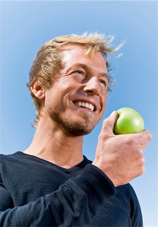 Man holding apple outdoors Stock Photo - Premium Royalty-Free, Code: 628-05817581