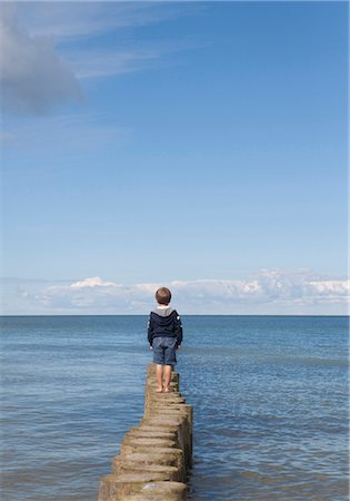 pic of a lonely person standing alone - Boy standing on groynes at the ocean Stock Photo - Premium Royalty-Free, Code: 628-05817767