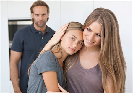 father and daughter hug - Daughter und mother close together with father in background Stock Photo - Premium Royalty-Free, Code: 628-05817769