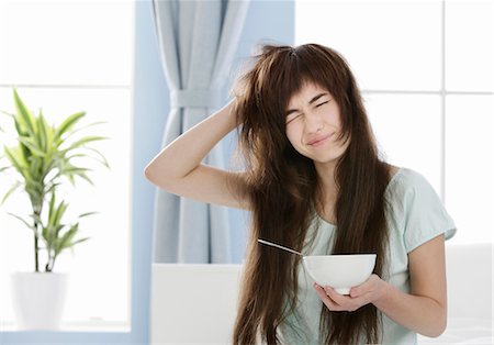 sleepy lazy person - Young woman with muesli bowl disheveling her hair Stock Photo - Premium Royalty-Free, Code: 628-05817830