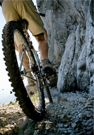 success path - Mountainbiker riding on narrow trail at rock face Stock Photo - Premium Royalty-Free, Code: 628-05817916