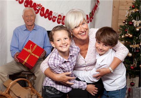 simsearch:628-07072165,k - Grand-mère embrassant les petits-enfants à l'arbre de Noël Photographie de stock - Premium Libres de Droits, Code: 628-05817974