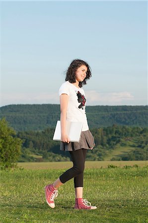 Girl walking with laptop in meadow Stock Photo - Premium Royalty-Free, Code: 628-07072118