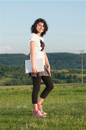 Girl walking with laptop in meadow Stock Photo - Premium Royalty-Free, Code: 628-07072120