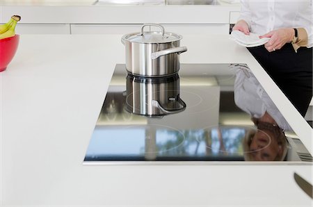 person with appliance - Woman standing in kitchen with pot on stove Stock Photo - Premium Royalty-Free, Code: 628-07072155