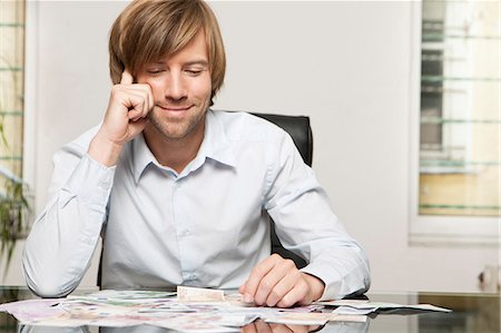 people saving money - Smiling man at desk looking at banknotes Stock Photo - Premium Royalty-Free, Code: 628-07072203