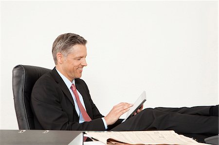 economy newspaper - Smiling manager at desk using tablet computer Stock Photo - Premium Royalty-Free, Code: 628-07072217