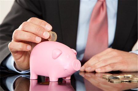 piggy bank - Businessman putting coin into piggy bank Stock Photo - Premium Royalty-Free, Code: 628-07072224