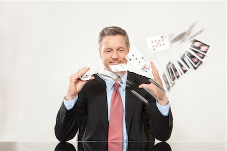 playing cards - Smiling businessman playing with cards at desk Stock Photo - Premium Royalty-Free, Code: 628-07072229