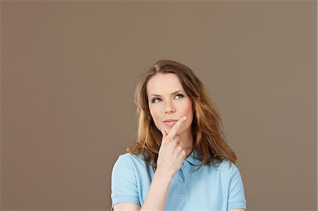 Young woman in blue polo shirt thinking Stock Photo - Premium Royalty-Free, Code: 628-07072243