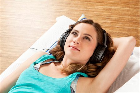 pillow and cushion - Young woman listening to music with headphones Stock Photo - Premium Royalty-Free, Code: 628-07072272