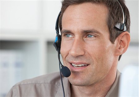 phone in front of face - Man wearing headset in office Stock Photo - Premium Royalty-Free, Code: 628-07072500