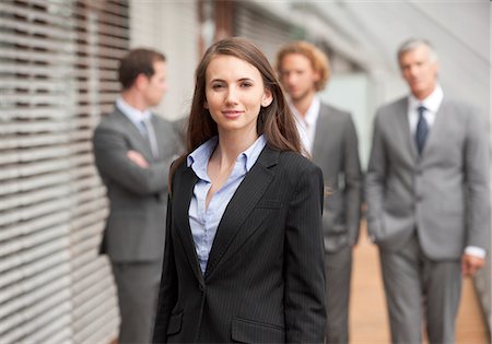 powerful women in office suits - Smiling businesswoman in front of group of businessmen Stock Photo - Premium Royalty-Free, Code: 628-07072534