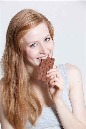 simsearch:628-07072594,k - Redheaded young woman eating chocolate Photographie de stock - Premium Libres de Droits, Code: 628-07072625