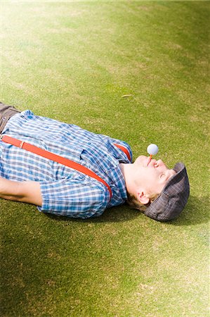 Man laying on golf course with a golf ball in his mouth Photographie de stock - Premium Libres de Droits, Code: 628-07072635