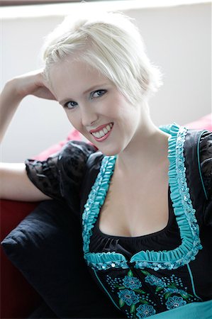 sofa floral - Smiling young woman on couch wearing a dirndl Stock Photo - Premium Royalty-Free, Code: 628-07072686