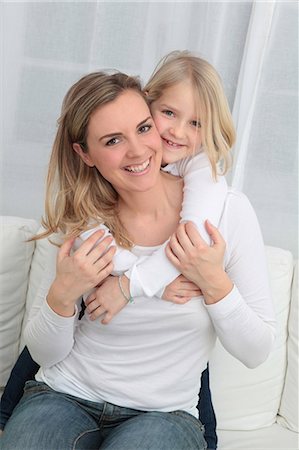 sitting down jeans - Mother and daughter cuddling on couch Foto de stock - Sin royalties Premium, Código: 628-07072725