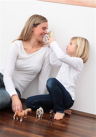 smiling girl on horse - Mother and daughter playing with horse figures on the floor Stock Photo - Premium Royalty-Free, Code: 628-07072733