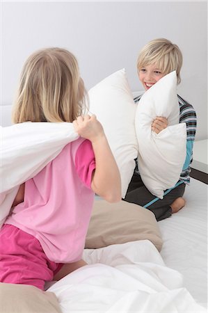 sister fights brother - Brother and sister having a pillow fight in bed Stock Photo - Premium Royalty-Free, Code: 628-07072757