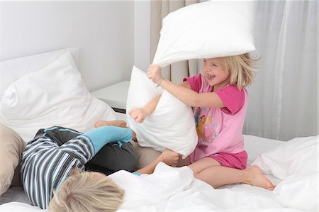 simsearch:628-05817540,k - Brother and sister having a pillow fight in bed Photographie de stock - Premium Libres de Droits, Code: 628-07072758