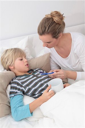 Mother taking the temperature of sick son in bed Foto de stock - Sin royalties Premium, Código: 628-07072759