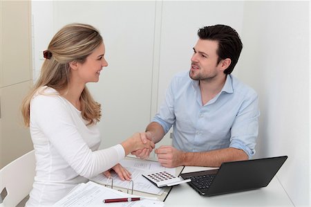Man and woman shaking hands at table with file, calculator and laptop Stock Photo - Premium Royalty-Free, Code: 628-07072750