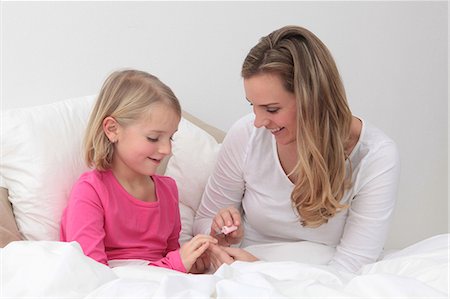 feminine objects - Mother applying nail polish to daughter in bed Stock Photo - Premium Royalty-Free, Code: 628-07072763