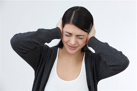 plugging ears - Serious young woman holding her head in hands Photographie de stock - Premium Libres de Droits, Code: 628-07072830