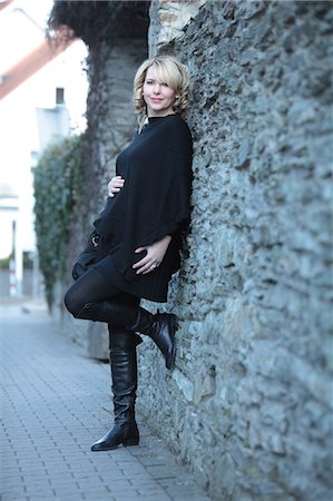 female pregnant belly expansion - Pregnant woman leaning against stone wall Stock Photo - Premium Royalty-Free, Code: 628-07072879