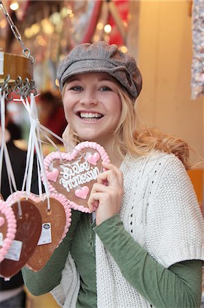 portraits kitschy - Happy woman with gingerbread heart on a funfair Stock Photo - Premium Royalty-Free, Code: 628-07072936