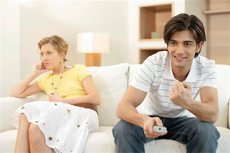 Man watching TV, bored young woman sitting on sofa Stock Photo - Premium Royalty-Free, Code: 628-00918637