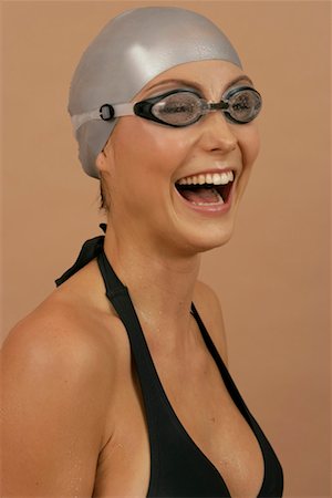 Laughing female swimmer wearing a bathing cap and goggles Stock Photo - Premium Royalty-Free, Code: 628-00919047