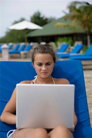 Young girl sitting on a deck chair, using laptop Stock Photo - Premium Royalty-Free, Code: 628-00919223