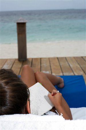 Young girl sitting at a deck chair, writing holiday diary Stock Photo - Premium Royalty-Free, Code: 628-00919241
