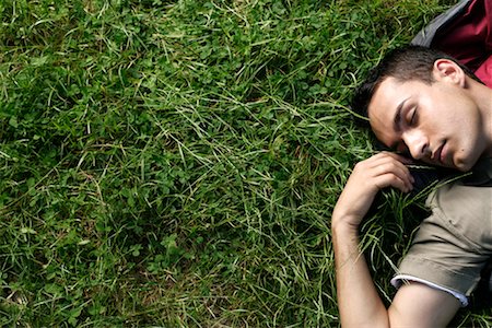 Young man sleeping in sleeping bag on grass Stock Photo - Premium Royalty-Free, Code: 628-00919717