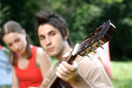 Young couple sitting side by side while he is playing the guitar Foto de stock - Sin royalties Premium, Código: 628-00919727