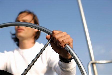 Man at the steering wheel of a sailboat Stock Photo - Premium Royalty-Free, Code: 628-00919913