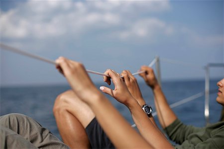 friends sailing - Couple holding on a safety line on a sailboat Stock Photo - Premium Royalty-Free, Code: 628-00919933