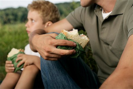 simsearch:628-00919973,k - Father and son sitting on meadow while they eat sandwiches Stock Photo - Premium Royalty-Free, Code: 628-00919986