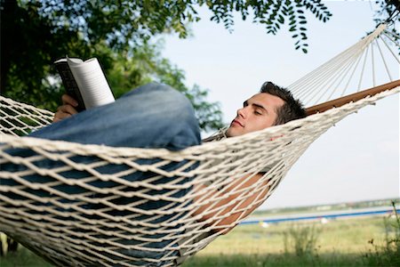 Man lying in hammock and reading Stock Photo - Premium Royalty-Free, Code: 628-00920043