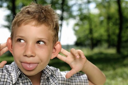 sticking out her tongue - Boy making a grimace at camera Stock Photo - Premium Royalty-Free, Code: 628-00920064