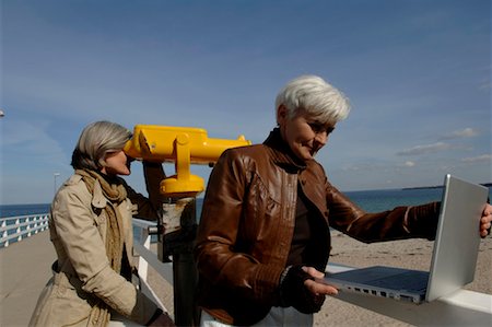 simsearch:628-00920280,k - Femme mature en regardant à travers une jumelles payantes sur la plage de la mer Baltique, une autre femme à l'aide d'un ordinateur portable Photographie de stock - Premium Libres de Droits, Code: 628-00920277